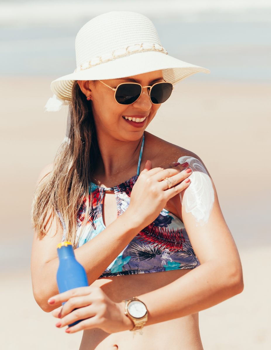 Woman at the beach applying sunscreen